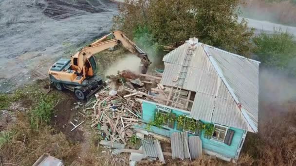 Rivning av byggnader. en grävmaskin bryter ner gammalt byhus. — Stockvideo