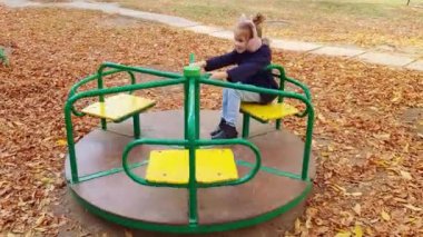 Gözü morarmış bir kız sonbaharda avluda bir atlıkarıncaya biniyor. çürük