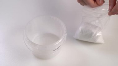 Büyüyen kristaller için ayarlandı. Beyaz kristal tozu bir kabın içine dökülüyor.