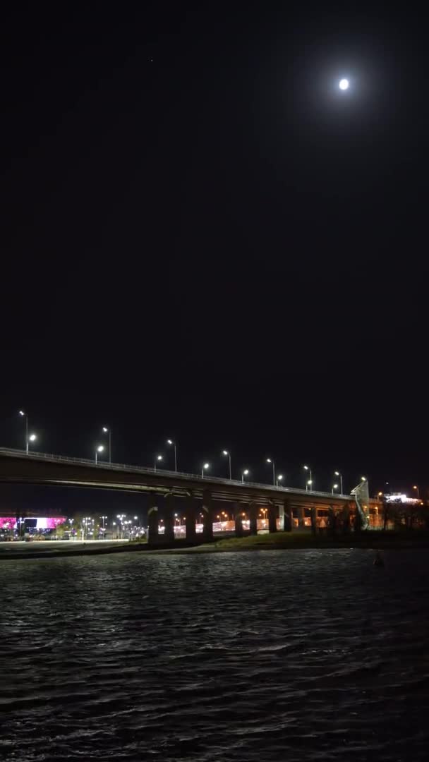 Függőleges videó. Jó éjt. közúti híd a folyó felett fényekkel és mozgó autókkal. — Stock videók