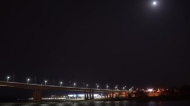 İyi geceler. Nehrin üzerindeki yol köprüsünde ışıklar ve hareket halindeki arabalar.