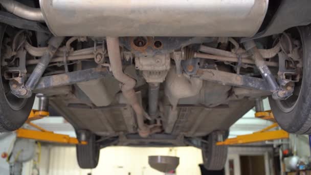 Afvoer van afgewerkte olie en technische inspectie van de auto Nissan op de lift in de garage. — Stockvideo