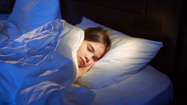Dospívající dívka spí v posteli, vidí příjemný spánek a usměje se. — Stock video