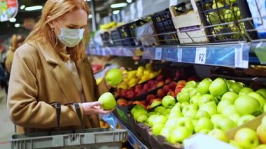 Koruyucu, tek kullanımlık maskeli bir kadın süpermarketten alışveriş yapıyor.
