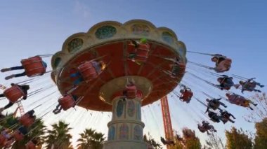 Lunaparkta geziyor. İnsanlar salıncaklara biner, rahatlar ve eğlenirler.. 
