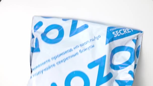 Un colis dans un emballage avec le logo ozon tombe sur un fond blanc. — Video