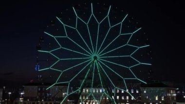 Hızlandırılmış. Gece gökyüzüne karşı parlayan çok renkli ışıkları olan dönme dolap.