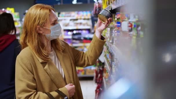 Uma mulher com uma máscara protetora descartável, fazendo compras no supermercado — Vídeo de Stock