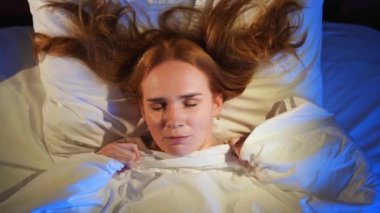 Üstten bak. Kızıl saçlı bir kadın yatakta uyur ve bir kabus görür.. 