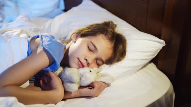 Hezká dospívající dívka spí s plyšovou hračkou, vidí příjemný spánek a usměje se. — Stock video