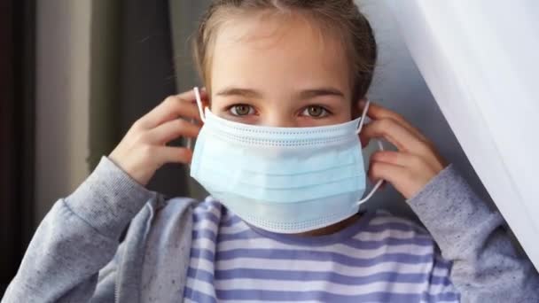 Una adolescente lleva una máscara médica protectora desechable. — Vídeos de Stock