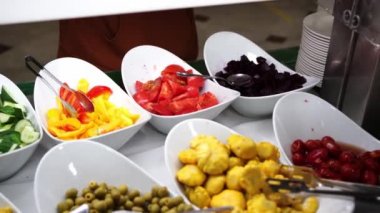 Kahvaltı, otelde büfe. İnsanlar tabaklarına yemek koyar.