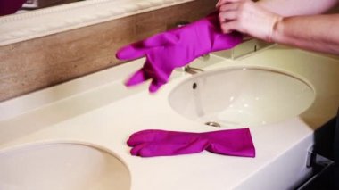 Banyoyu temizlemeden önce, kadın ellerine kauçuk koruyucu eldiven takıyor.