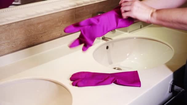 Před úklidem koupelny si žena navlékne ruce gumové ochranné rukavice — Stock video