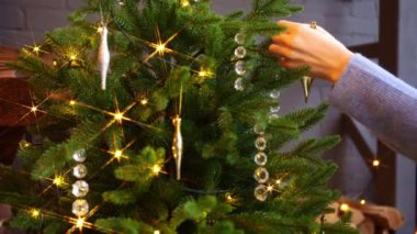 Bir kadın şöminenin yanındaki kır evinde Noel ağacını süslüyor.