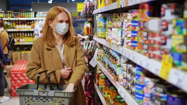 Seorang wanita dengan topeng sekali pakai yang protektif, berbelanja di supermarket — Stok Video