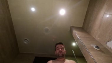 Bir su jeti. Adam banyo lavabosunda yüzünü yıkıyor. objektifteki su.