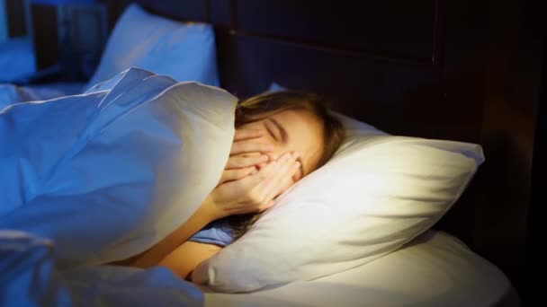 Nastolatka drzemie w łóżku i kaszle, kicha we śnie. — Wideo stockowe