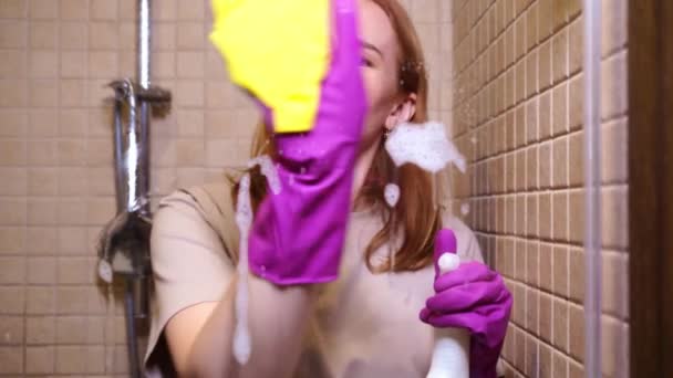 Woman in gloves, with detergent spray, rag washes a partition in the shower — Stock Video