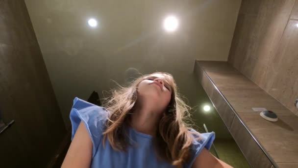 Сонная девушка идет в ванную и чистит зубы электрической щеткой над раковиной — стоковое видео