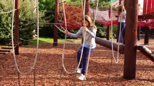 Дівчина грає у мотузковому парку. активні спортивні ігри для дітей на відкритому повітрі . — стокове відео