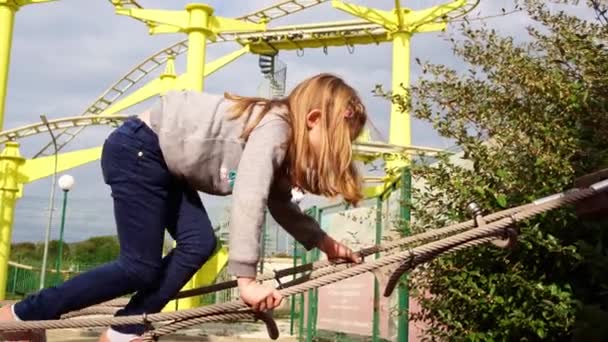 Una chica juega en un parque de cuerdas. activa, juegos deportivos para niños al aire libre. — Vídeos de Stock