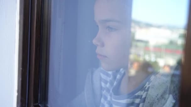 A través del vidrio. triste chica adolescente mirar por la ventana fuera. — Vídeos de Stock