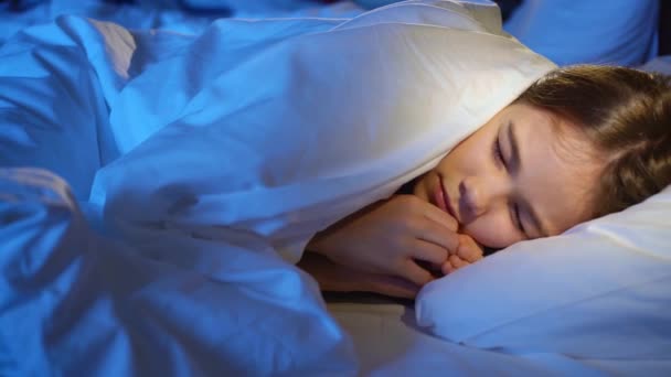 Uma menina dorme na cama em seu quarto, vê um pesadelo e winces em seu sono. — Vídeo de Stock