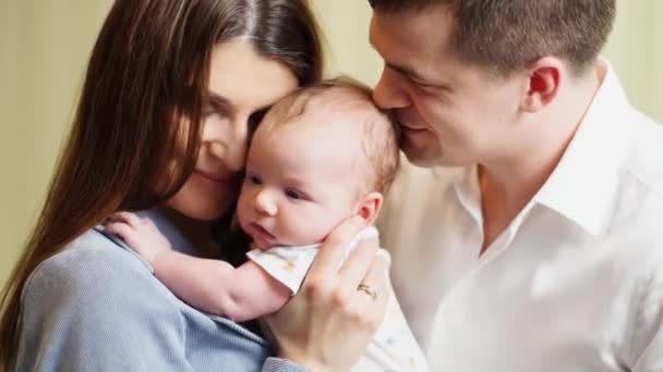 Мама з татом тримаються за руки і цілують немовлятко.. — стокове відео