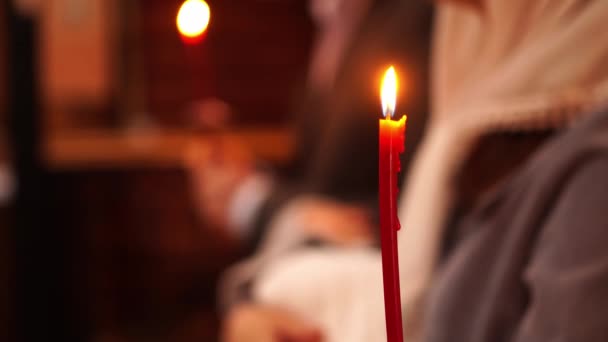 Brennende Kerze und eine Frau mit einem Kind im Arm bei einer Taufe in der Kirche. — Stockvideo