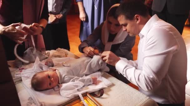 Family clothes a newborn baby after baptism in church. — ストック動画