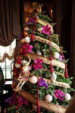 Eski tarz oyuncaklar ve çelenklerle süslenmiş Noel ağacı.