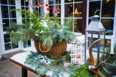 Yılbaşı süsleri karla kaplı bir kır evinin bahçesinde masa.