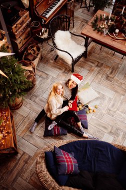 top view. Two woman lying on the floor by fireplace with New Years decoration.