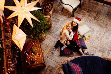 top view. Two woman lying on the floor by fireplace with New Years decoration.