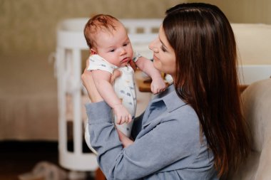 Mom gently holds on her kid in arm. long-awaited baby. Mothers Day.