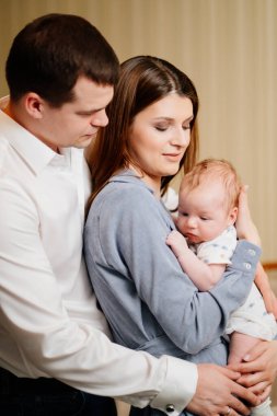 Mom and Dad hold in their arms the infant. 