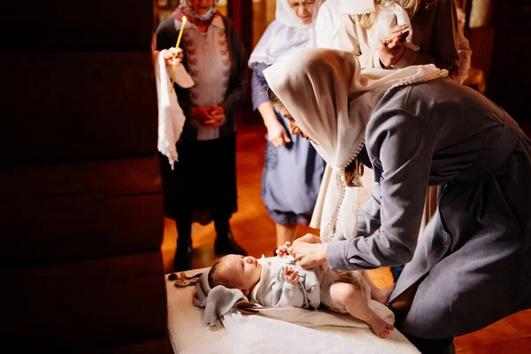 Mamma klär sitt barn i kyrkan på ett bord. dopets stadga,. — Stockfoto