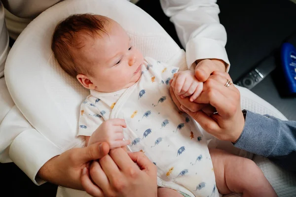 Ovanifrån. Lyckliga föräldrar föräldrar håller hand ung son i en solstol för nyfödda. — Stockfoto