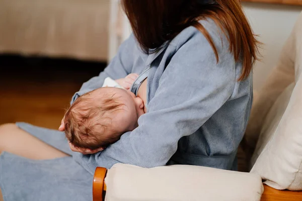 Mamma ammar en nyfödd hemma på soffan. fördelarna med amning — Stockfoto