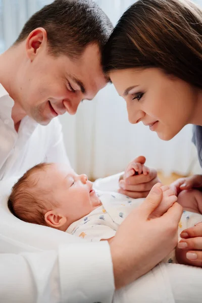 Pais felizes com filho jovem em uma espreguiçadeira para recém-nascidos. família amorosa — Fotografia de Stock