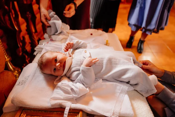 Barnet sätts på kläder på ett bord i kyrkan. dopets stadga,. — Stockfoto