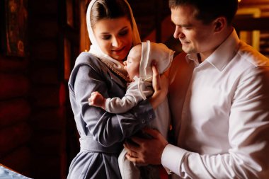 beautiful mom and dad in a headscarf with a small child in her arms in church. 