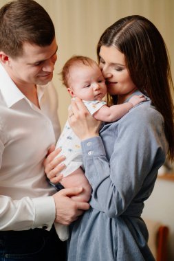 Mom and Dad hold in their arms the infant. 
