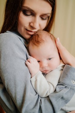 Mom gently holds on her kid in arm. long-awaited baby. Mothers Day.
