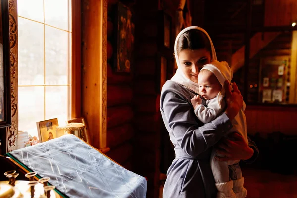 beautiful mom in a headscarf with a small child in her arms in church.