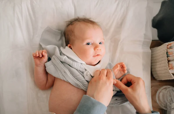 Vista superior. madres manos poner un mono en el bebé —  Fotos de Stock