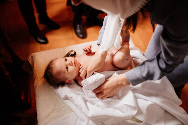 Мама одевает своего ребенка на стол в церкви. таинство крещения.