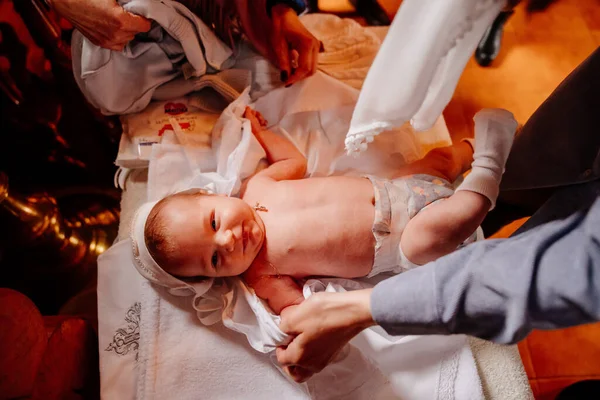 Eltern kleiden ihr Kind auf einen Tisch in der Kirche. die Verordnung über die Taufe. — Stockfoto