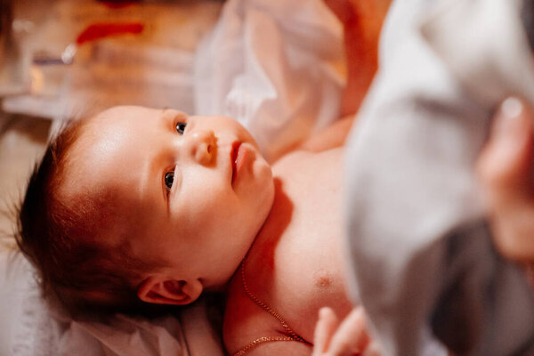 Ребенка одевают на стол в церкви. таинство крещения.